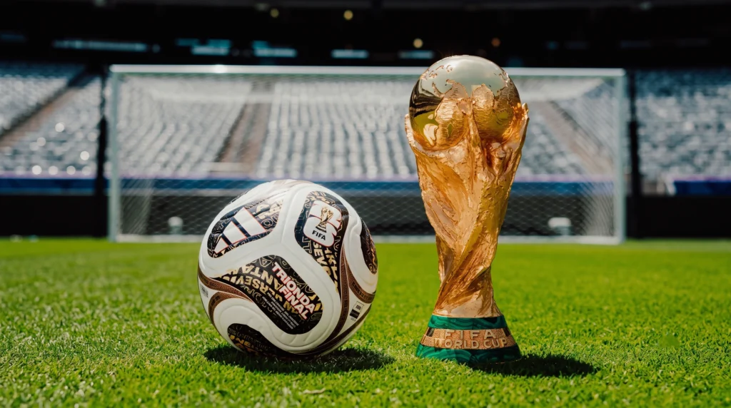 Texto alternativo (Alt Text):
Balon exclusivo Adidas Trionda Finals Pro junto al trofeo de la Copa del Mundo en el MetLife Stadium